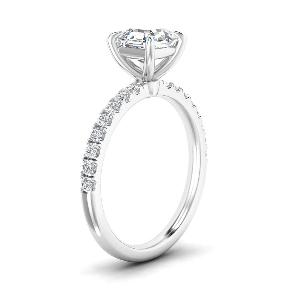 A white gold ring with a round diamond solitaire and smaller diamonds along the band, viewed from the side.