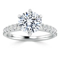 A white gold ring with a large round solitaire diamond and smaller diamonds set along the band.