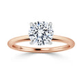 A rose gold ring with a large round solitaire diamond held by four prongs, shown on a white background.