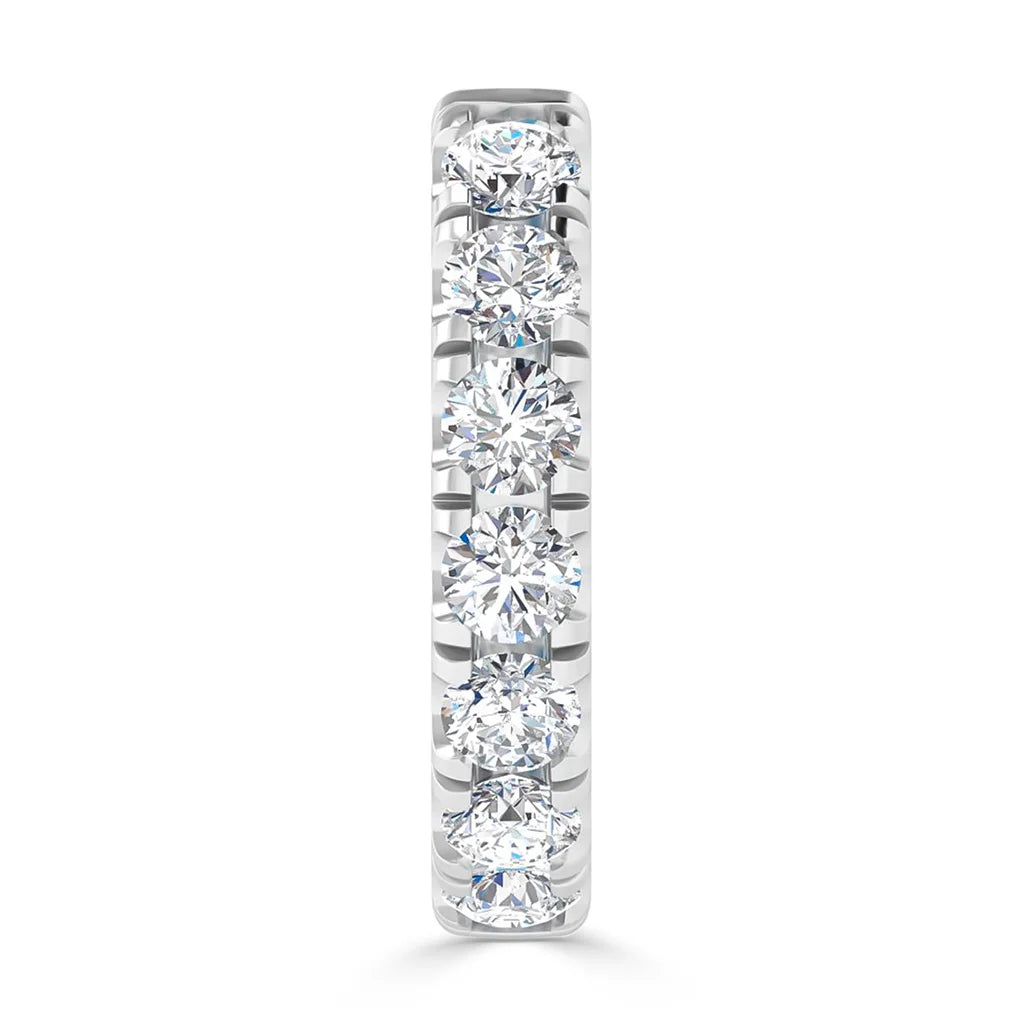 A silver ring with seven round, sparkling diamonds set in a single row along the band.