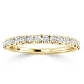 A thin yellow gold ring with a row of round white diamonds set along the top half of the band.