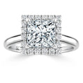 A square-cut diamond ring with a double halo of smaller diamonds on a simple silver band.