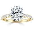 Gold ring with an oval-cut diamond center and diamond accents along the band, set against a white background.