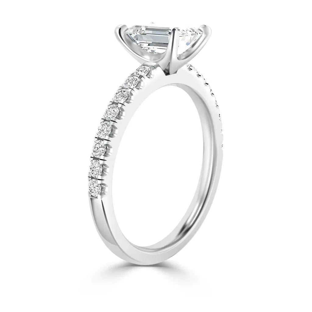 White gold ring with a prong-set oval diamond and small round diamonds along the upper half of the band.